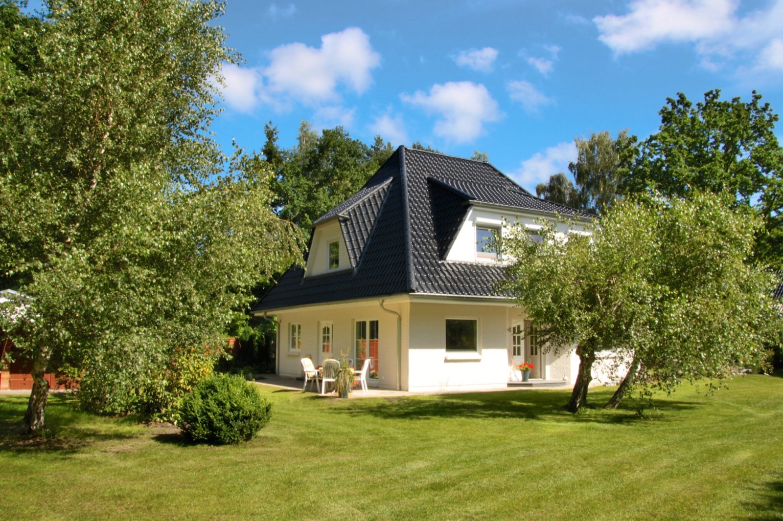 Das Ferienhaus Birkennest mit Garten und Terrasse unter blauem Himmel