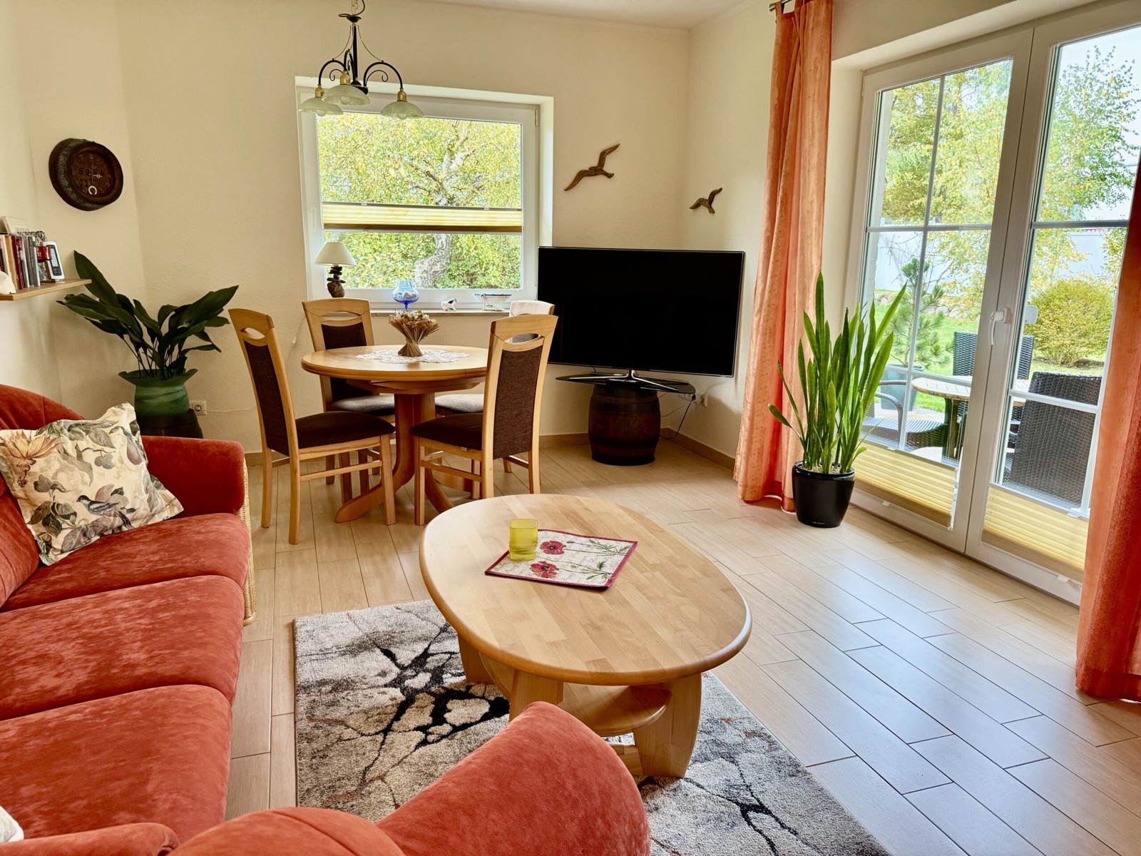 Helles Wohnzimmer mit rotem Sofa, Essplatz und Gartenfenster